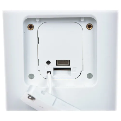 Zbliżenie na tylną część urządzenia elektronicznego z widocznym portem USB i przyciskiem resetowania. Obudowa jest biała, a wokół portu znajdują się dwa otwory montażowe.