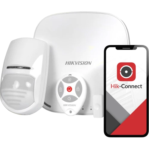 Na zdjęciu znajduje się bezprzewodowy system alarmowy Hikvision, składający się z centrali, czujnika ruchu, pilota oraz aplikacji mobilnej Hik-Connect widocznej na ekranie smartfona. Wszystkie elementy są w kolorze białym, a logo Hikvision jest wyraźnie widoczne na każdym z nich.