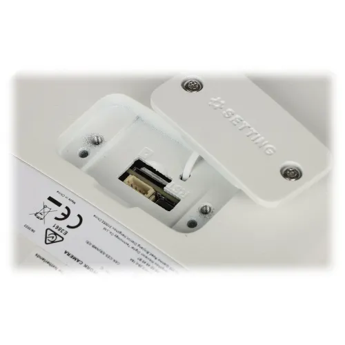 Zdjęcie przedstawia gniazdo karty pamięci oraz przycisk reset umieszczone na białej obudowie urządzenia. Obok znajduje się etykieta z oznaczeniami CE i symbolem przekreślonego kosza.