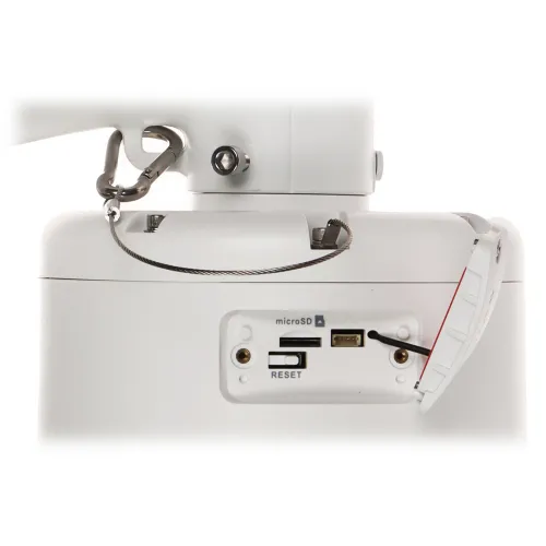 Zdjęcie przedstawia białe urządzenie z otwartą pokrywą, ukazującą gniazdo na kartę microSD, port USB oraz przycisk reset. W tle widoczny jest metalowy uchwyt z karabińczykiem i stalową linką.