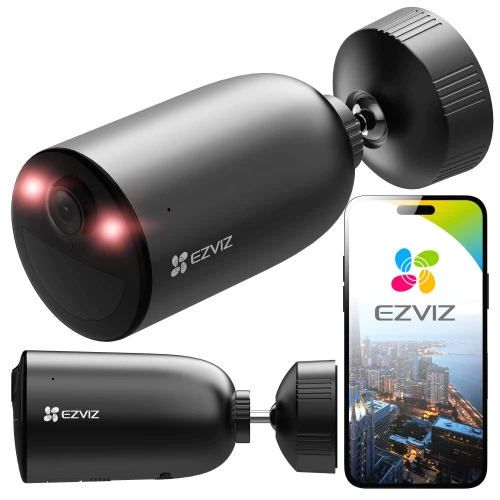 Na zdjęciu znajduje się czarna kamera monitoringu z własnym zasilaniem, obok której widoczny jest smartfon z aplikacją EZVIZ pokazującą widok z kamery. Kamera ma cylindryczny kształt i jest wyposażona w dwa czerwone diody LED.