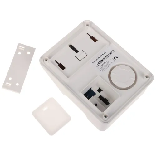 Zdjęcie przedstawia wnętrze białej obudowy elektronicznej z widocznymi złączami i miejscem na baterie. Obok obudowy leżą dwie zdejmowane pokrywy.